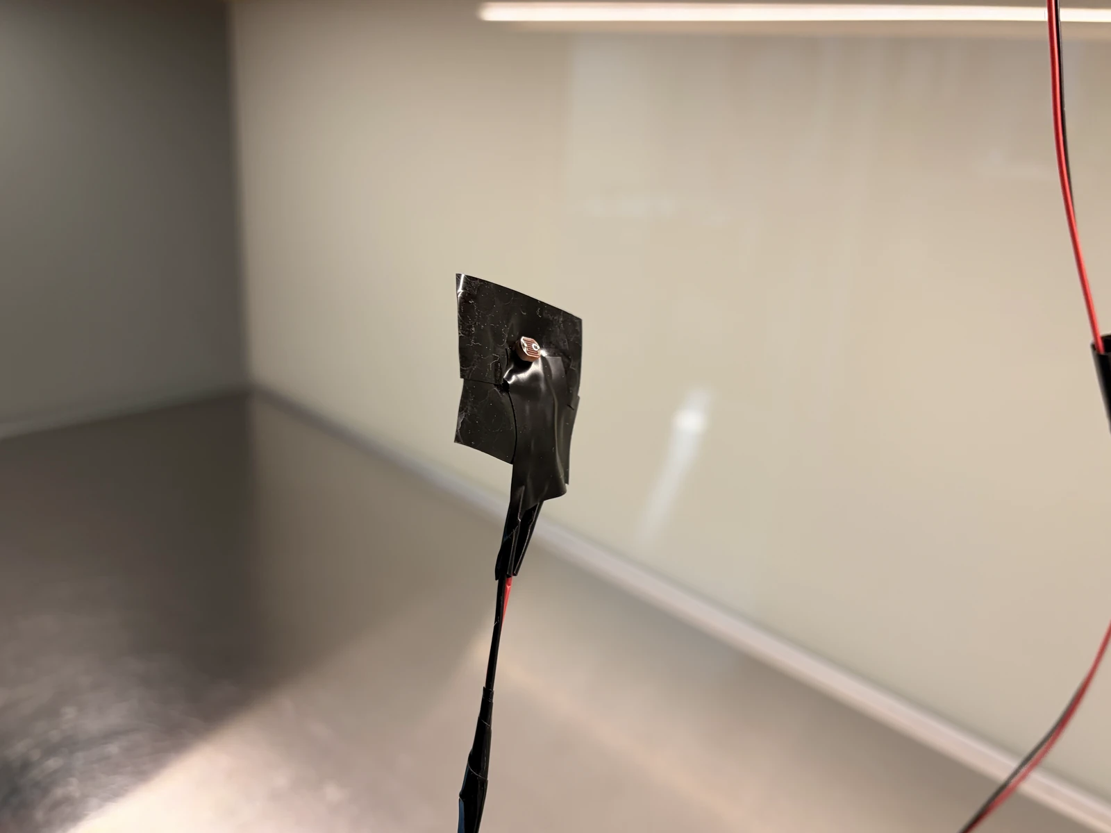 An LDR photosensor taped in black electrical tape at the end of a red and black wire